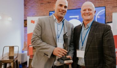 Two men stand with one holding an award