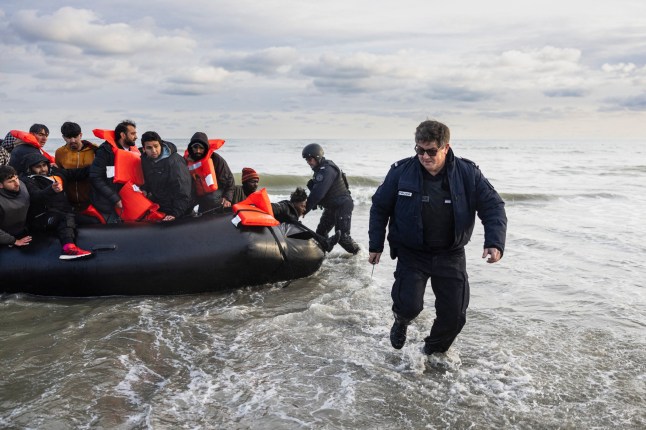 (FILES) French police officers puncture a smuggler's boat with a knife to prevent migrants from embarking in an attempt to cross the English Channelon the beach of Gravelines, near Dunkirk, northern France on April 26, 2024. London and Paris unveiled a "pilot" programme on July 10, 2025 to return to France some of the migrants arriving in the UK on small boats across the Channel. (Photo by Sameer Al-DOUMY / AFP) (Photo by SAMEER AL-DOUMY/AFP via Getty Images)
