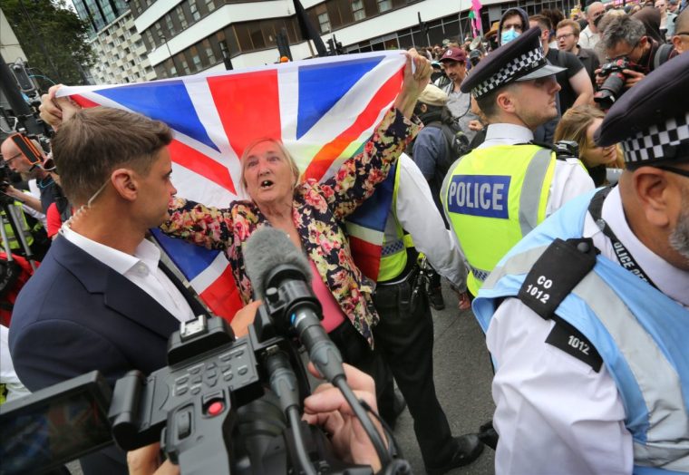 LONDON, ENGLAND - AUGUST 2: A protester against the asylum hotel carries a Union flag as she is talked to by the media during the protest on August 2, 2025 in London, England. Far-right protests focusing on hotels housing asylum seekers have increased in recent weeks, organised by far-right protest groups such as the Democratic Football Lads Alliance (DFLA). Stand Up To Racism (SUTR) is holding counter-protests defending refugees at many of the sites, with more protests expected over the summer. (Photo by Martin Pope/Getty Images)