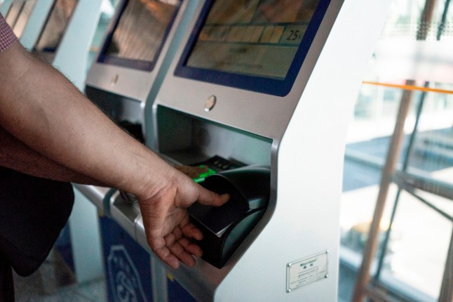 A traveller having their fingerprints taken at a scanner in airport.