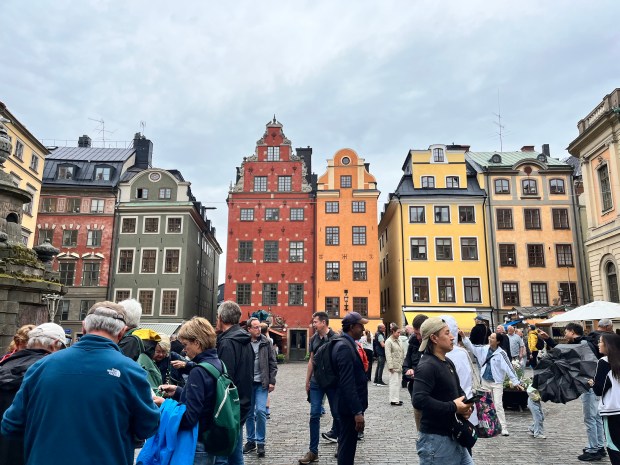 People in a square. There are colorful row houses in the background
