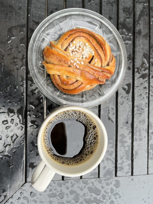 coffee and a cinnamon roll on a damp table