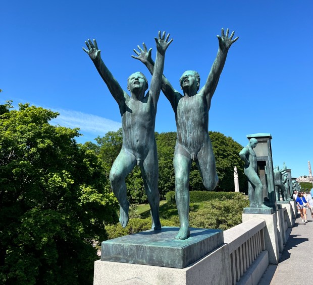 Two boys run with their hands in the air in this bronze sculpture