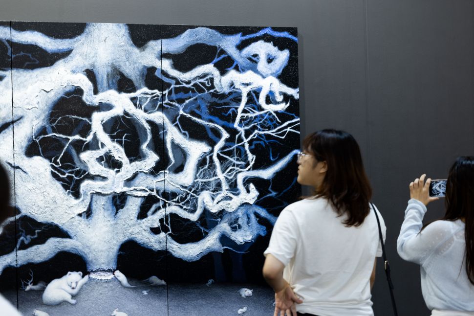 Visitors photograph a dramatic black-and-white tree painting.