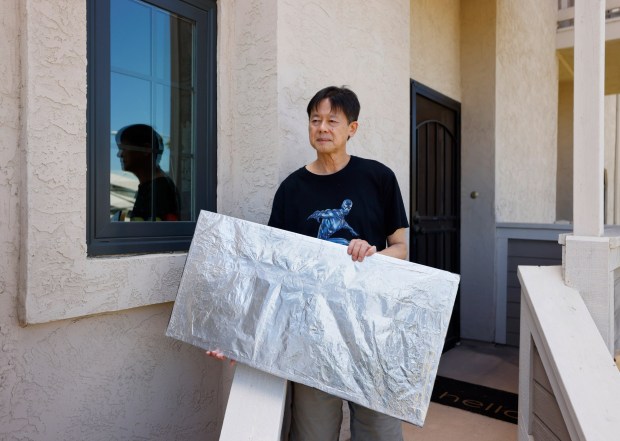 Soo Hom holds a foam panel that he uses to cover his windows to regulate temperature and keep his energy bill down at his University City home on July 21, 2025 in San Diego, California. (K.C. Alfred / The San Diego Union-Tribune)