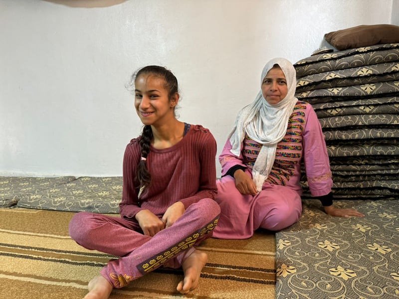 Hamda Al-Aql sits behind her daughter at the Mafraq camp refugee settlement near Zarqa, Jordan, in 2025.
