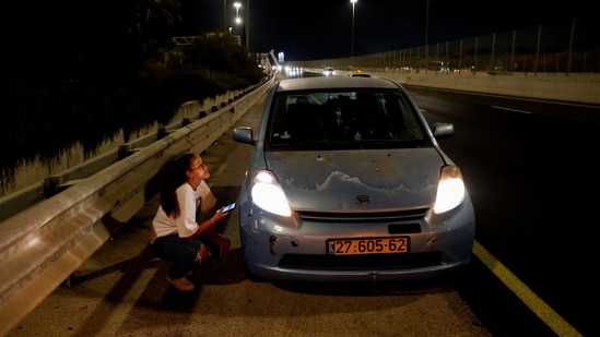 A woman takes cover behind a car, which stopped at the side of a road, while sirens sound, in response to what the Israeli military reported was a missile launched from Yemen towards Israel that was intercepted, in Tel Aviv, Israel, July 29, 2025.(Reuters)