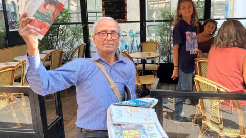 BBC Ali Akbar tur augšā Le Monde kopiju kafejnīcas priekšā Parīzes centrā