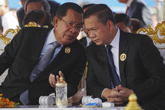 Cambodian Senate President Hun Sen, left, talks with his son, Prime Minister Hun Manet, during the 74th founding anniversary in Phnom Penh, Cambodia, on June 28. [AP/YONHAP]