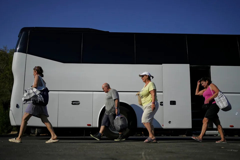 People arrive by bus at Avlaki beach about 42 kilometers (26 miles) east of Athens, Greece, Wednesday, Aug. 19, 2025. (AP Photo/Thanassis Stavrakis) (Copyright 2025 The Associated Press. All rights reserved)