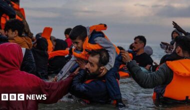 Migrant families wade into the sea in an attempt to board a small boat on 12 August 2025 in Gravelines, France.