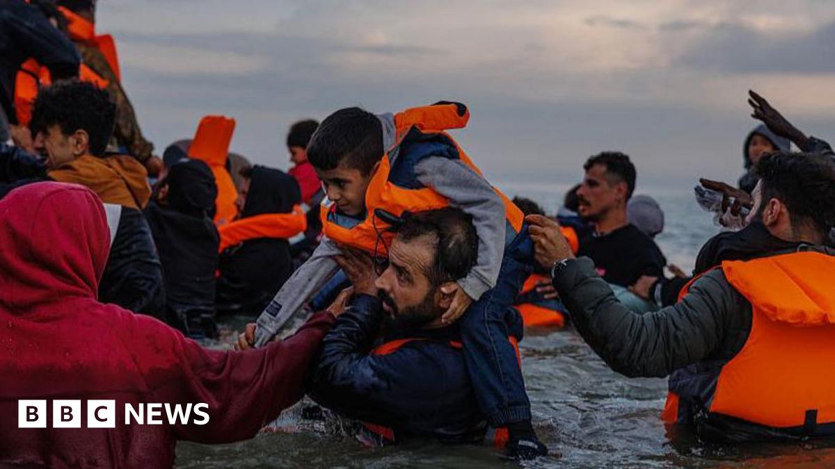 Migrant families wade into the sea in an attempt to board a small boat on 12 August 2025 in Gravelines, France.
