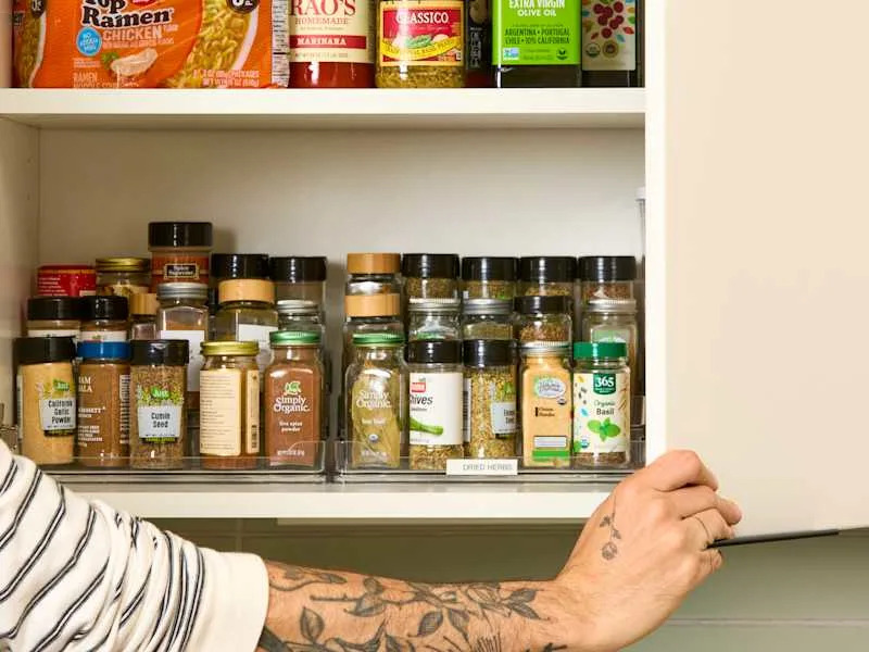 head on shot of an assortment of spices and other pantry items in a kitchen cabinet.