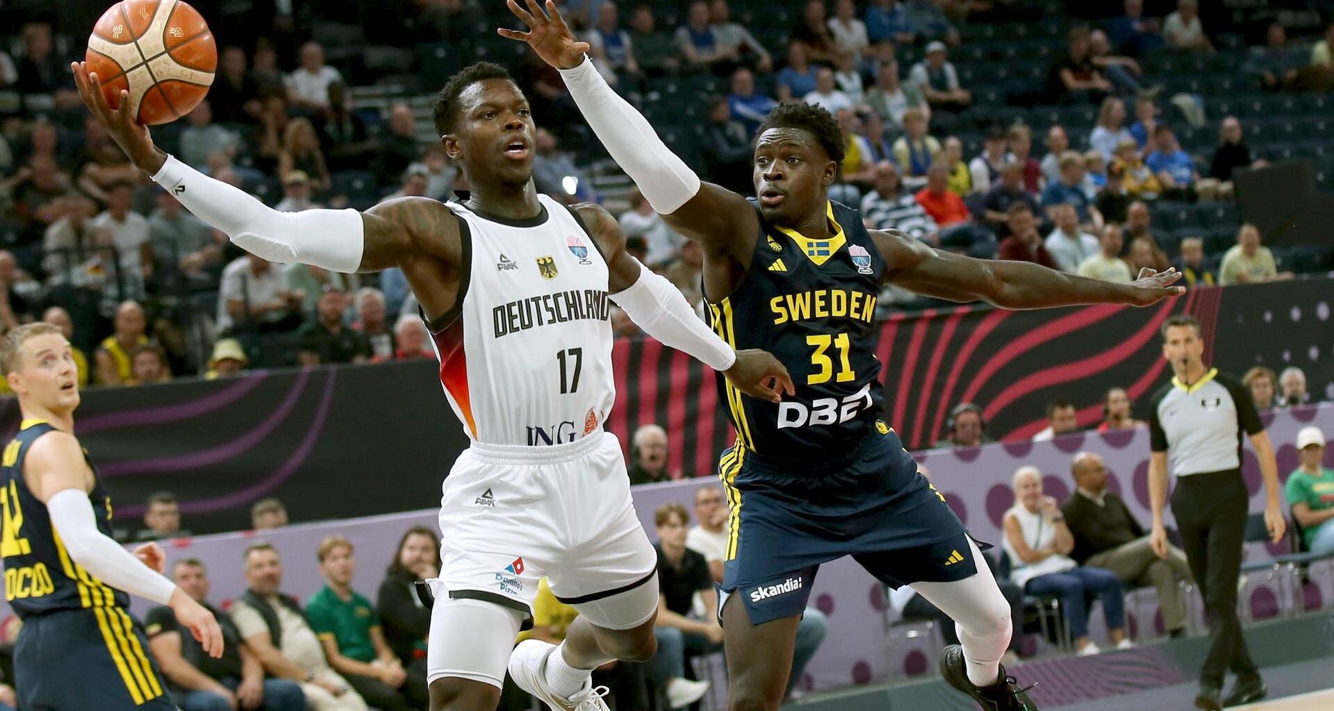 Das Bild zeigt Baskeballer Dennis Schröder beim Korbwurf, neben ihm ist ein Gegenspieler zu sehen.