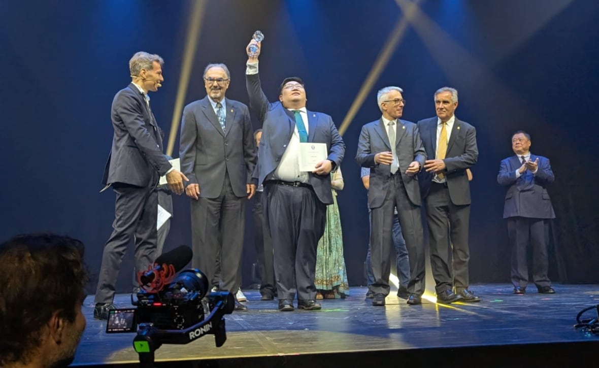 A man holding up an award on a stage. 