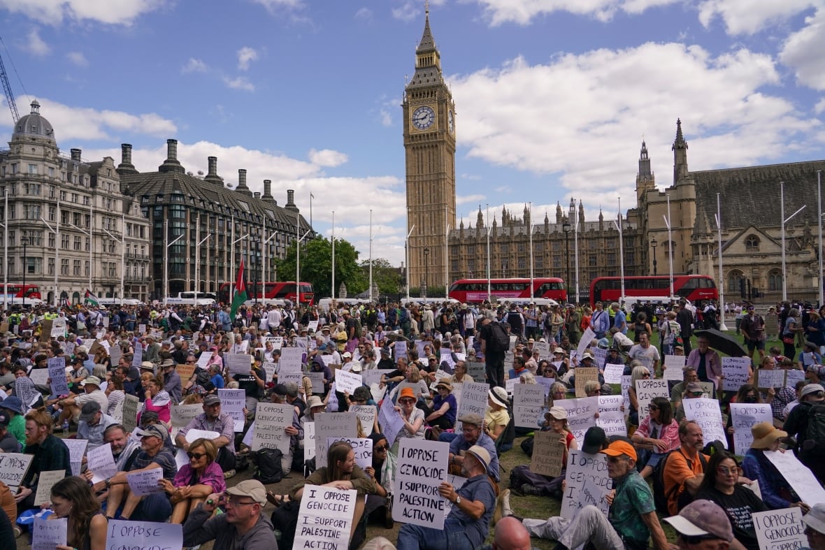 Demonstrators hold placards while sitting in public.