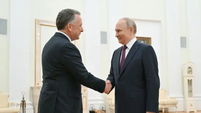 Steve Witkoff and Putin wear suits and smile and shake hands.