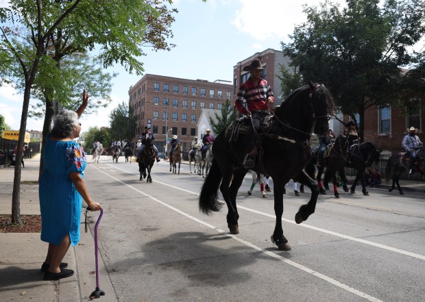 A woman waves as a rider on horseback participates in the Pilsen Mexican Independence Day Parade on Sept. 9, 2023. (Talia Sprague/Chicago Tribune)
