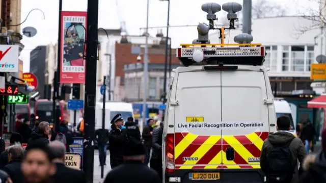 A facial recognition van being used by the Metropolitan Police in south London in 2024. The van has cameras on the roof and a sign on the back saying "Live Facial Recognition in Operation".