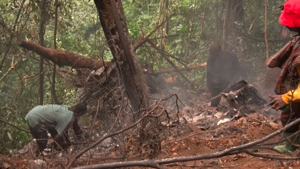 In this image taken from video, a man carries bodies retrieved from the military helicopter crash in Sikaman near Adansi, Ashanti region, Ghana, Wednesday, Aug. 6, 2025