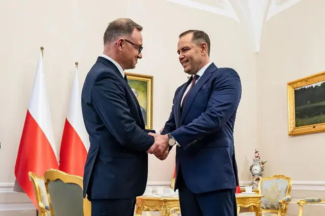 Andrzej Duda, urzędujący prezydent Polski (z lewej), oraz Karol Nawrocki, prezydent elekt, ściskają sobie dłonie w Pałacu Prezydenckim w Warszawie.