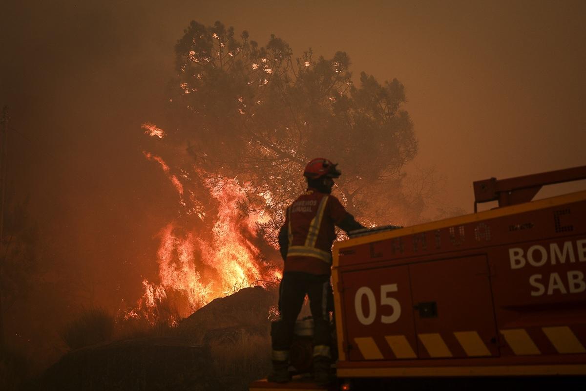 A firefighter stands at a firefighter truck as a wildfire approaches Benvende village, in Trancoso, Portugal. Photo: AFP