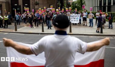 A man holds a flare during a protest outside The Bell Hotel on July 31, 2025 in Epping, England.