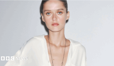 A pale model poses in a white Zara shirt staring at the camera with a blank expression and the low cut design of the top shows her protruding collarbones