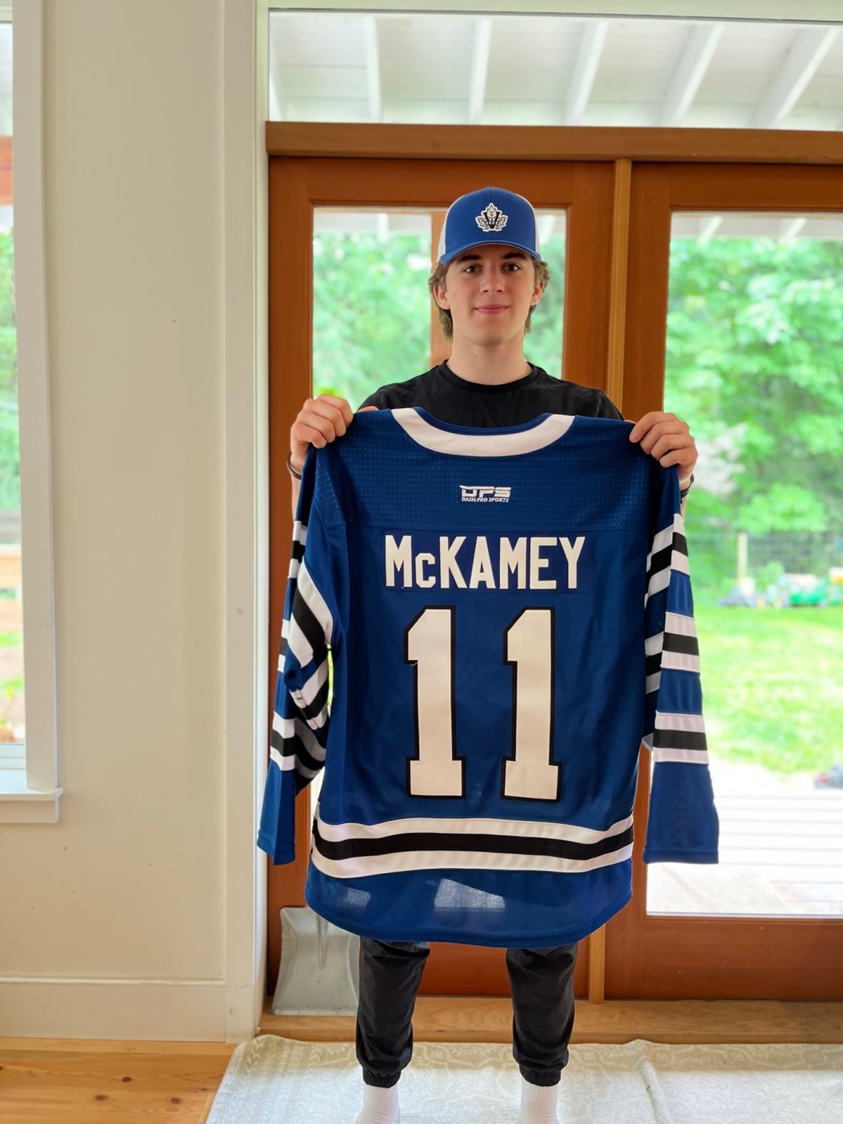 A young boy holds up a blue hockey jersey with his name on it.