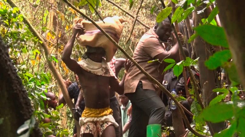 In this image taken from video, a man carries bodies retrieved from the military helicopter crash in Sikaman near Adansi, Ashanti region, Ghana, Wednesday, Aug. 6, 2025