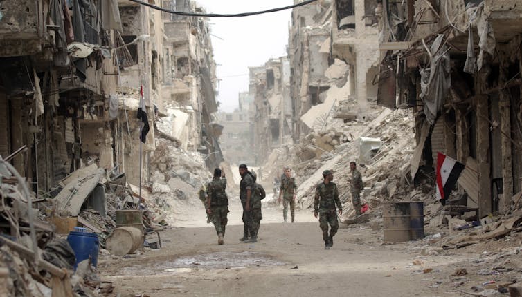 Syrian soldiers patrol a war-damaged neighbourhood of Damascus.
