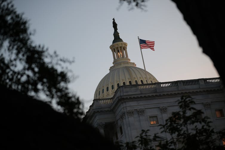 A view of the U.S. Capitol, with a U.S. flag flying in the foreground.