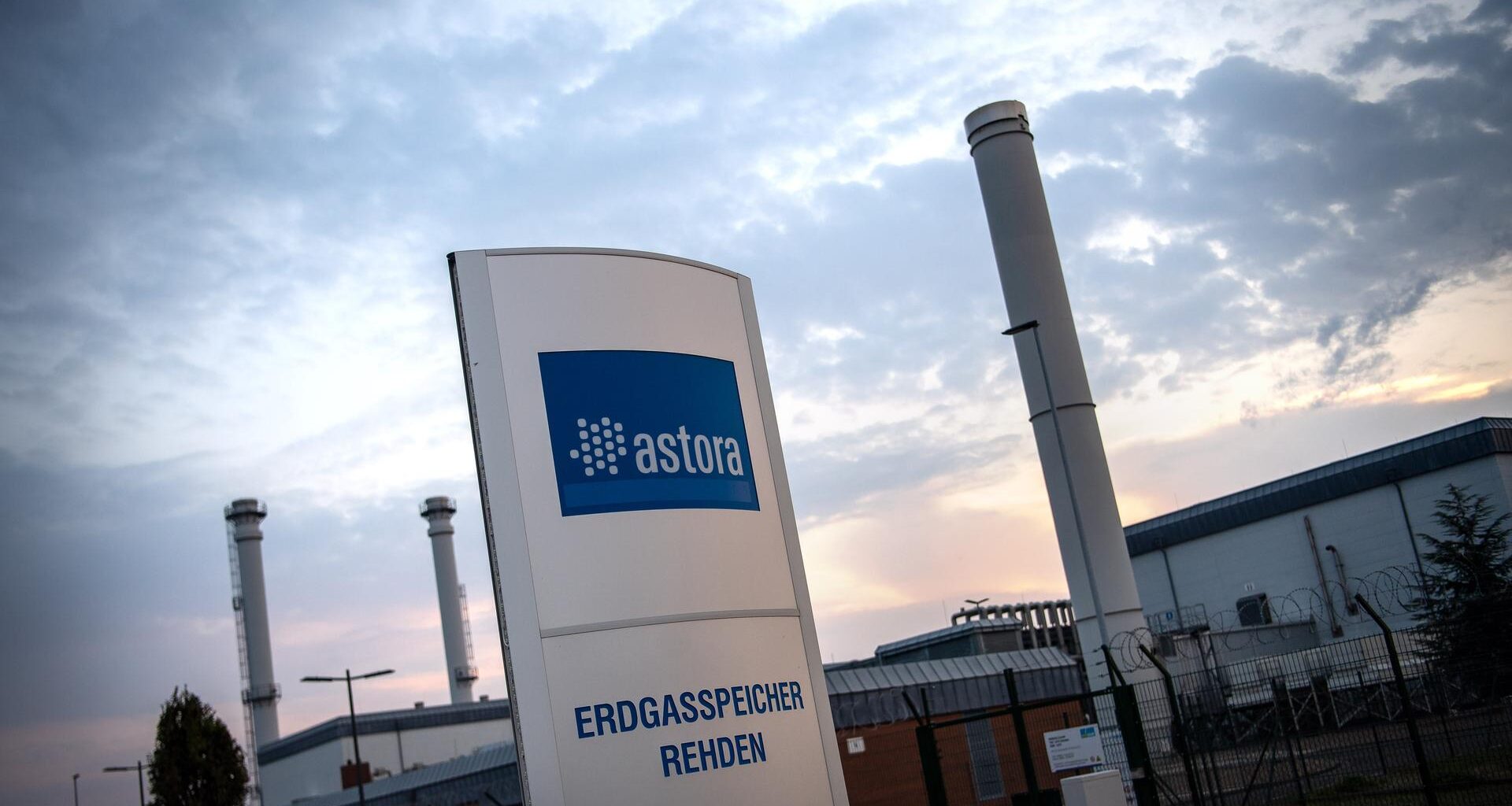 Schild mit der Aufschrift: "Astora. Erdgasspeicher Rehden", dahinter Industrieanlagen.