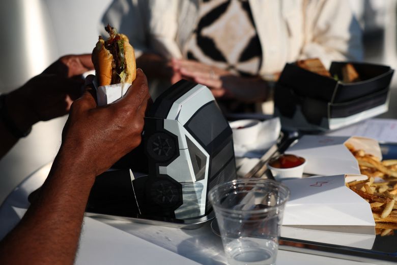 An attendee eats a Tesla burger from a Cybertruck-inspired box.