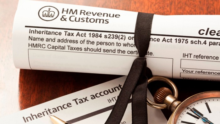 A rolled HM Revenue & Customs inheritance tax clearance certificate form tied with a black ribbon, an Inheritance Tax Account form, and a pocket watch