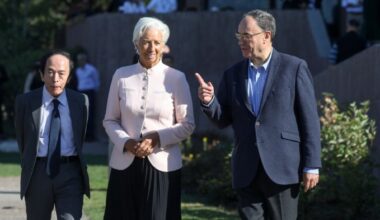Christine Lagarde, Kazuo Ueda, and Andrew Bailey walk together outdoors, with Bailey gesturing as they converse.