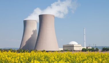 Nuclear power station with steaming cooling towers and canola field