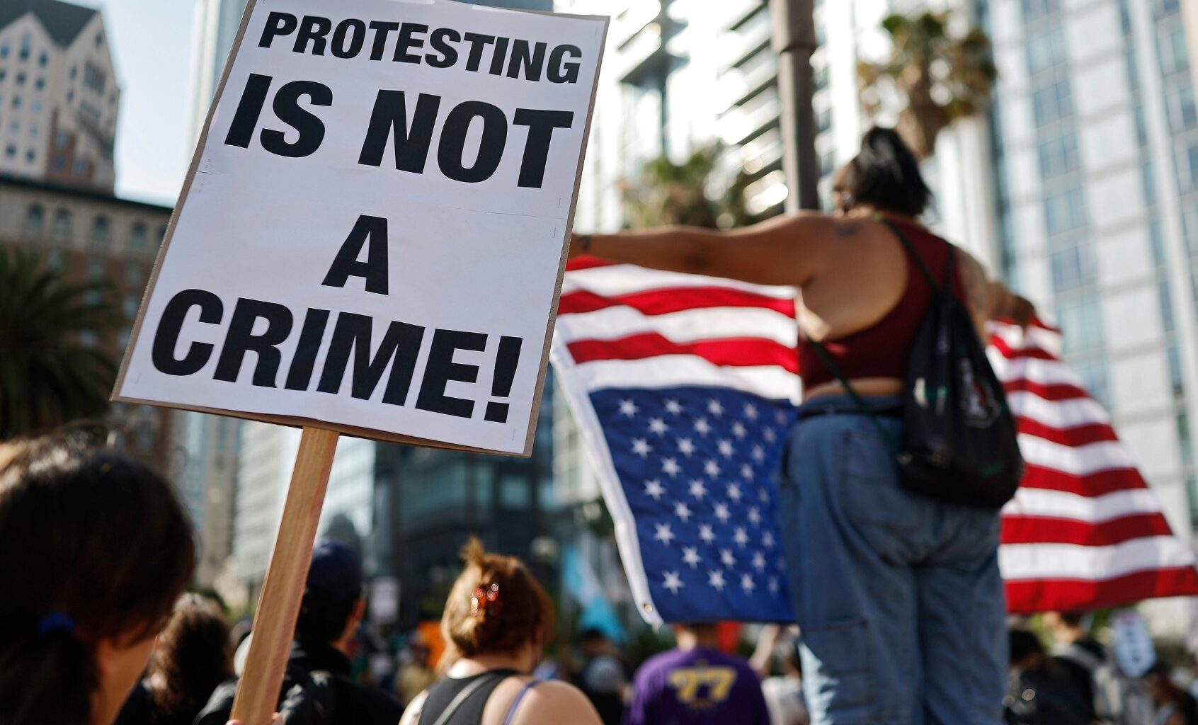 A person holds a "Protesting Is Not A Crime!" sign as people demonstrate before marching downtown as protests against ICE immigration raids continue in the city on June 11, 2025 in Los Angeles, California. (Mario Tama/Getty Images)