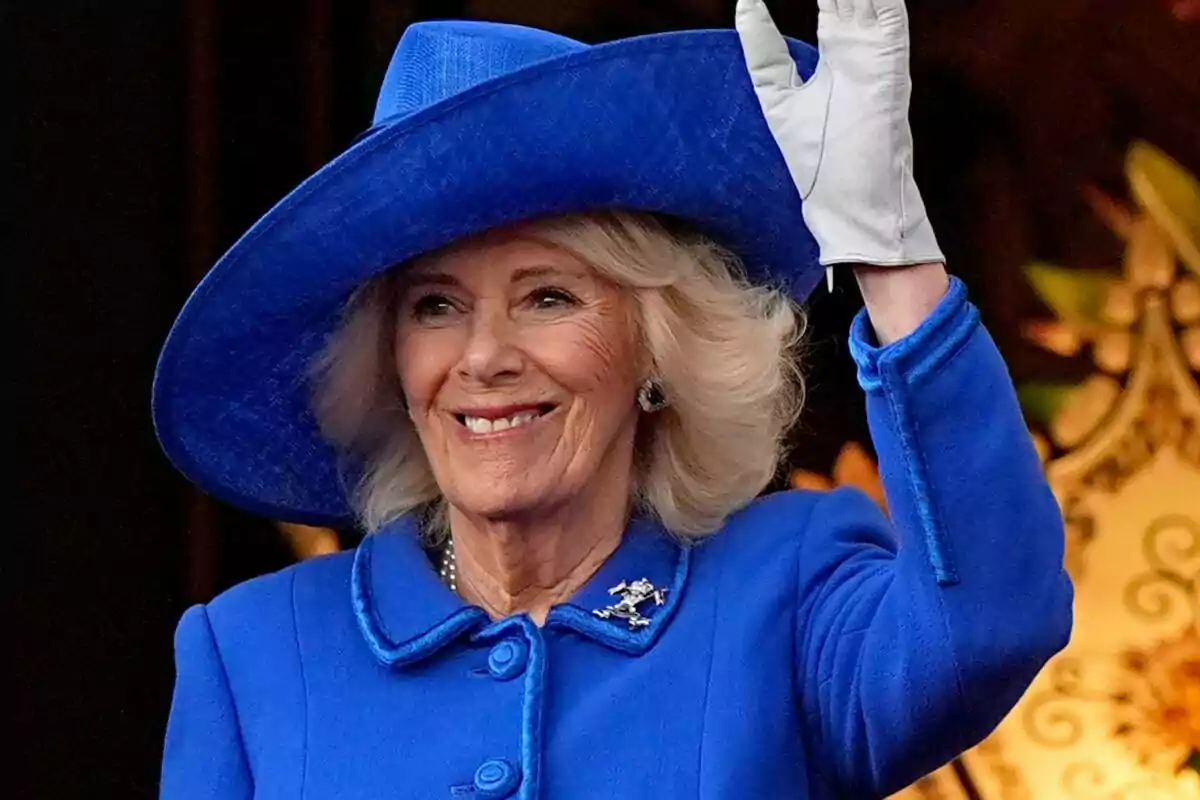 A smiling woman in a blue hat and coat waving.