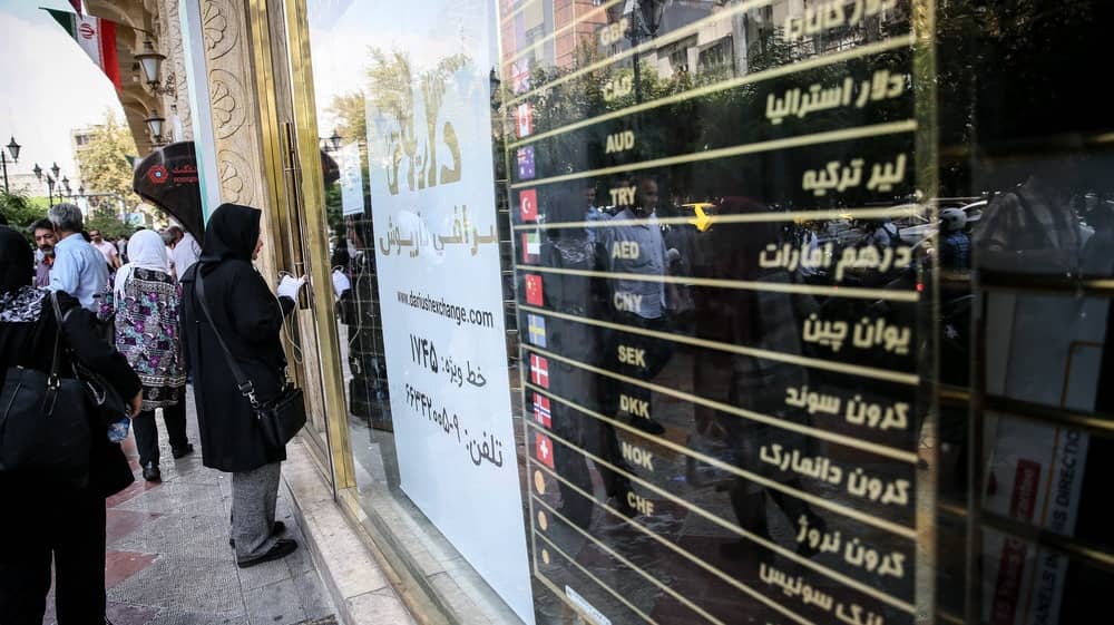 People gather outside a foreign exchange office in Tehran