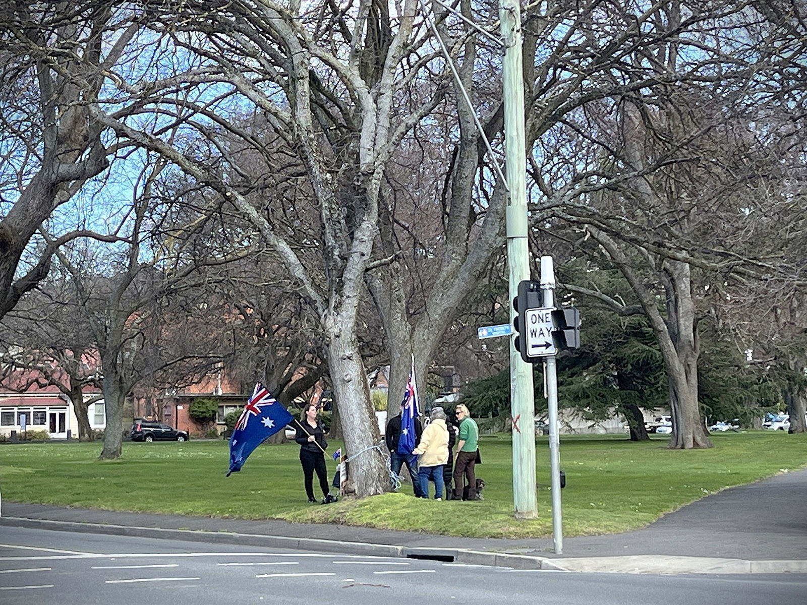 Five people standing near a tree, two with Australian flags