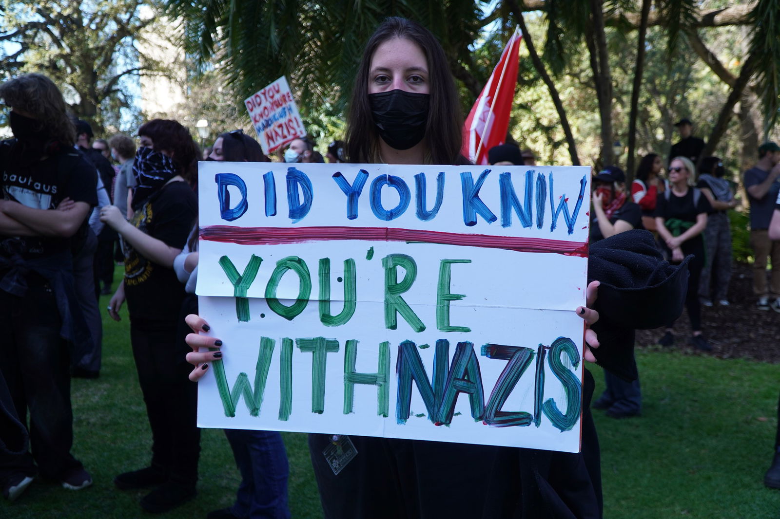 A protester holding a sign saying "did you know you're with nazis"