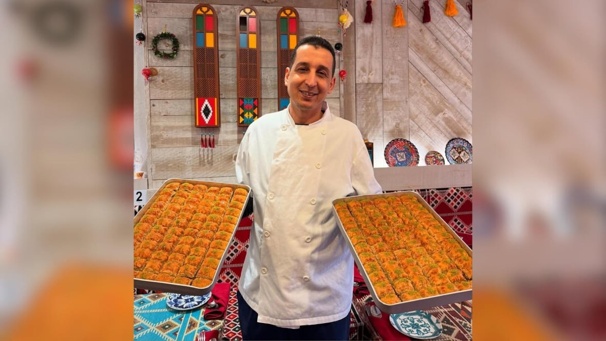 A person in a cook's jacket holds two baking sheets full of pastries.