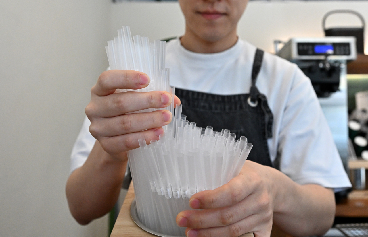 A cafe owner puts plastic straws out for customers on November 8, 2023. (Im Se-jun/The Korea Herald)