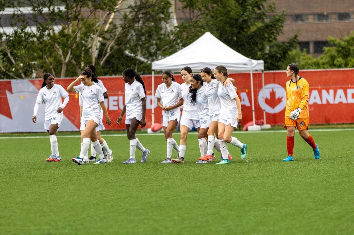 10 soccer players walking together on a field, some arm-in-arm.