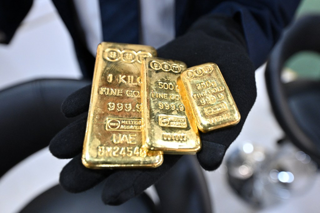 Person holding three gold bars.
