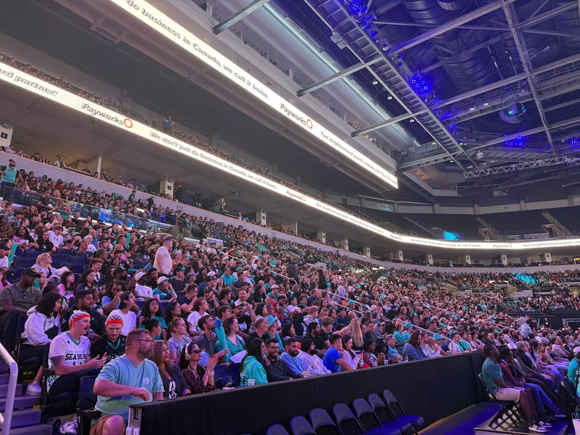 People sit in the stands watching a basketball game.