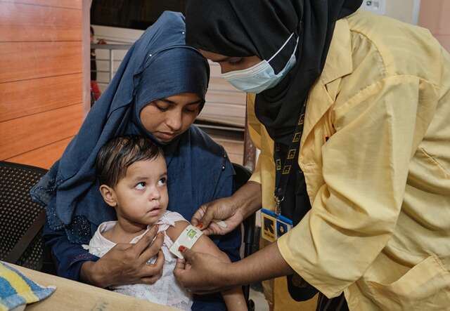 An IRC health care worker screens a young Rohingya child for signs of malnutrition.