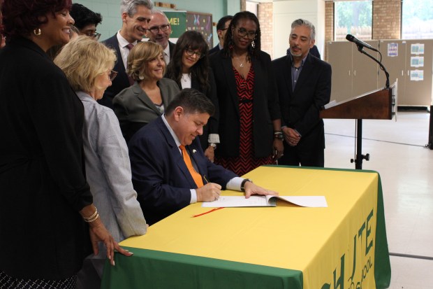 Gov. JB Pritzker at Chute Middle School in Evanston on July 31, 2025, signs into law a mandate that will require Illinois public schools to offer students between third and 12th grades an optional mental health screening. (Richard Requena/Pioneer Press)