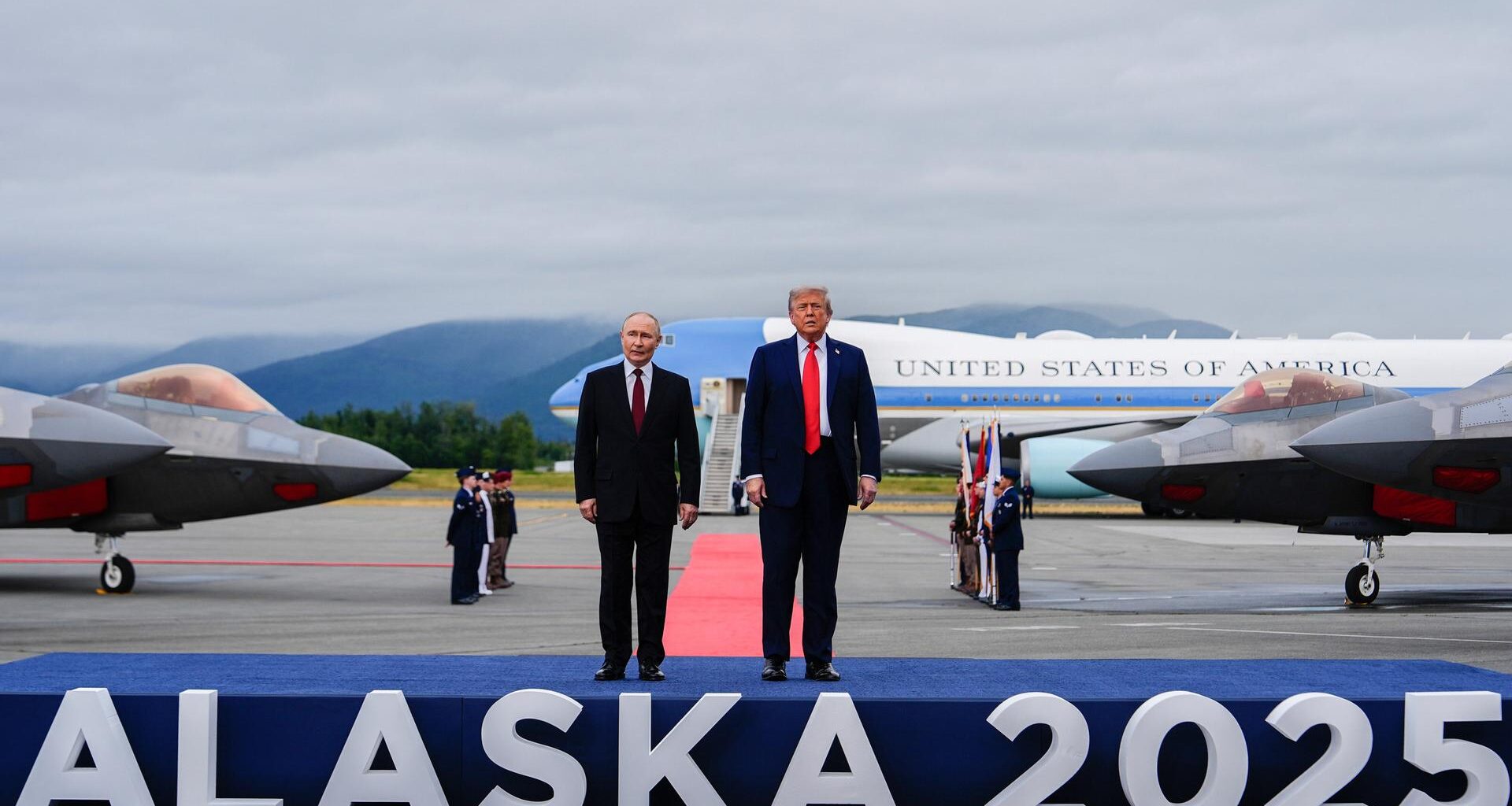 US-Präsident Donald Trump und der russische Präsident Wladimir Putin stehen auf einem Flughafen auf einem Podest, auf dem "Alaska 2025" steht.